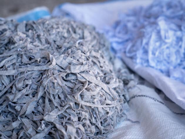 Fabric scraps, old clothing and textiles are cut into strips waiting for recycle.