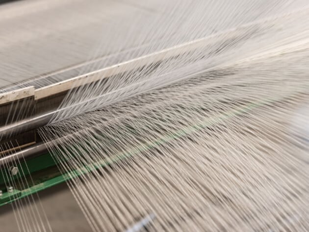 threads being woven into fabric.